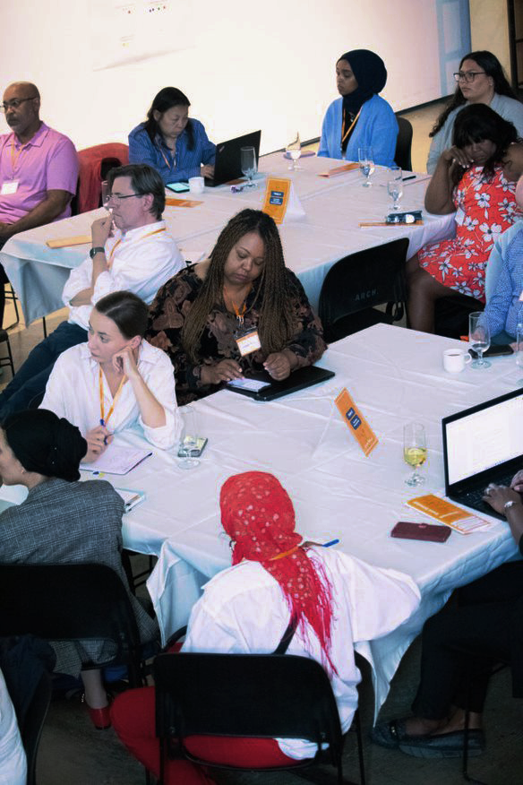 Several people sitting at tables with white table clothes.