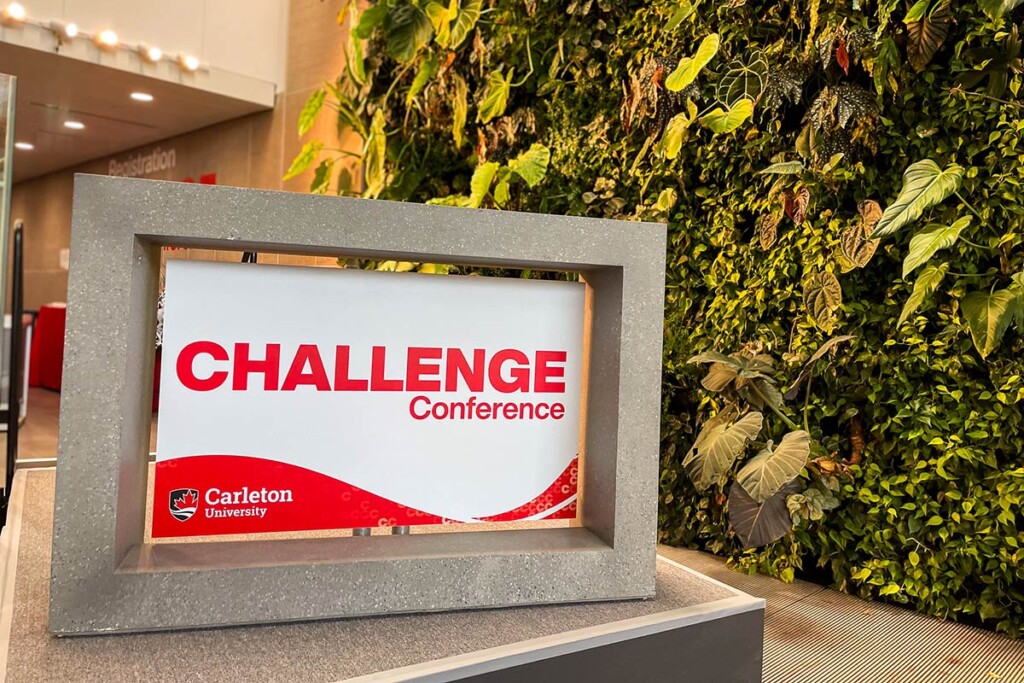 A red and white sign with the words Carleton Challenge Conference at The AI Summit