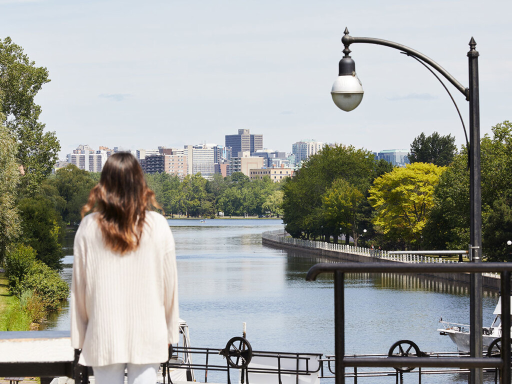 A woman with her back turned looks over a canal