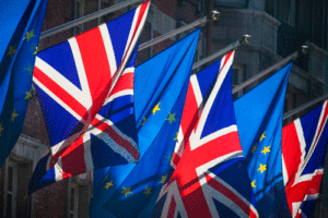European Union and United Kingdom flags flutter on a sunny day.