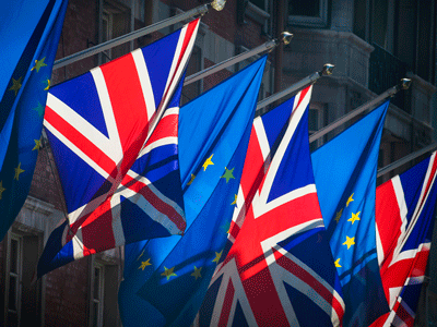 European Union and United Kingdom flags flutter on a sunny day.