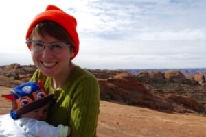 Prof. Rachel Buxton holds her child in a desert setting.