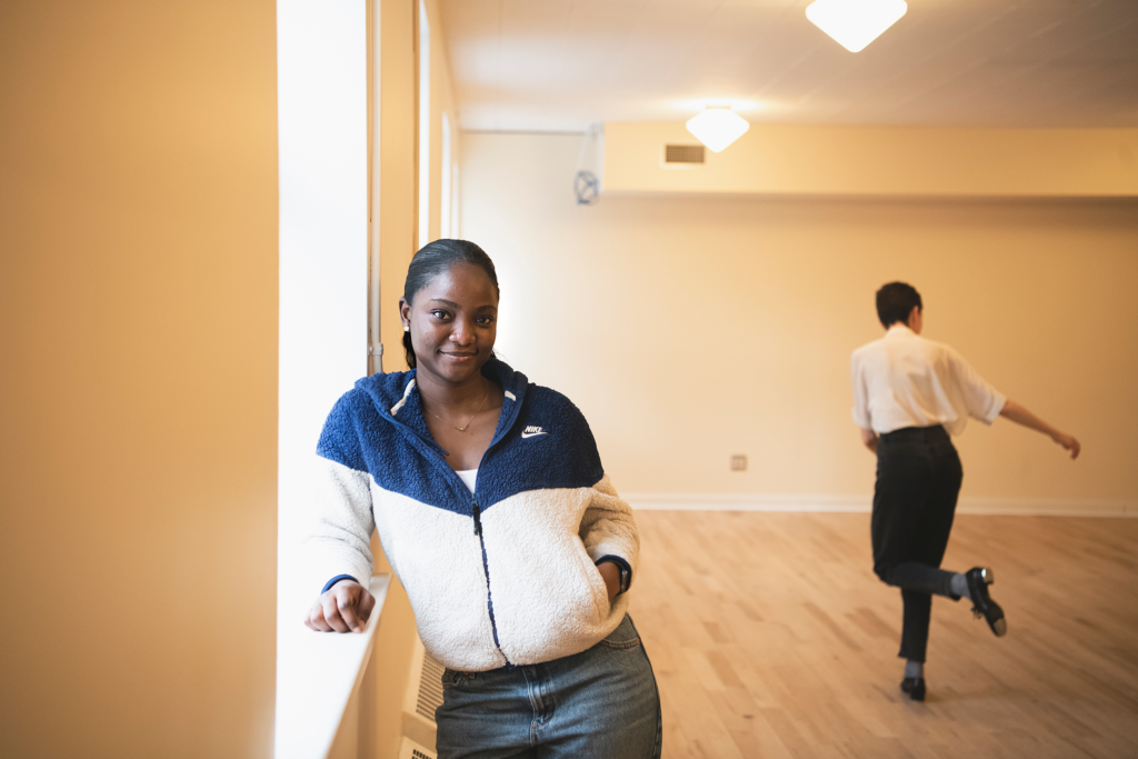 A woman leaning against a window sill poses for a photo.