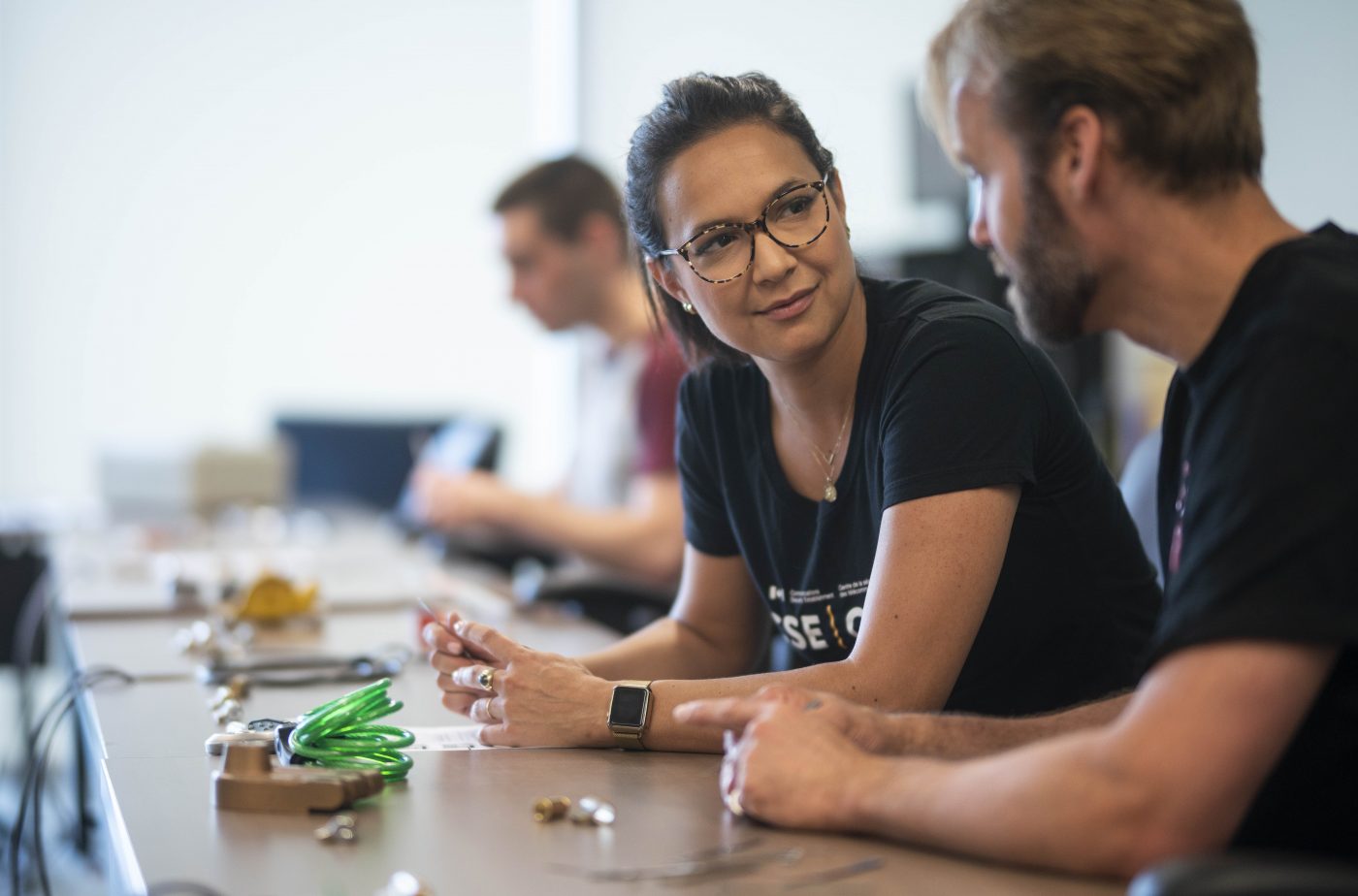 Participants at iHack speak while tinkering with an electronic device.