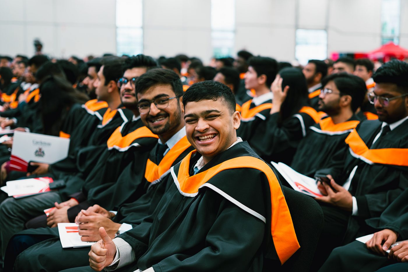 Seated students smile at a convocation ceremony.