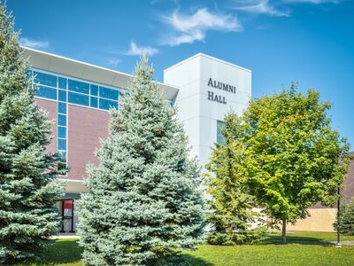 building with name Alumni Hall on the top with trees in front