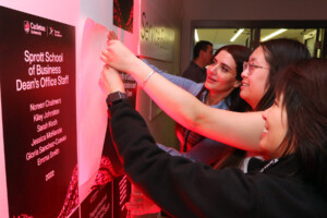 Three women placing an sticker award on a wall board