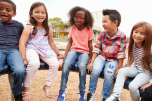 Five children sit together on playground equipment.