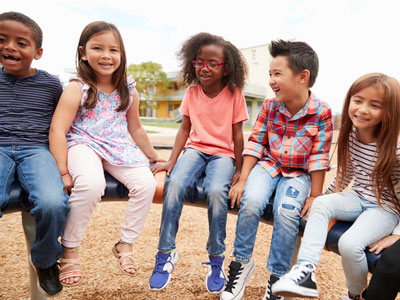 Five children sit together on playground equipment.