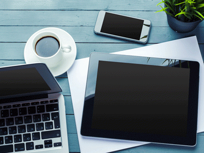 Computer electronics and a cup of coffee sit on a table.
