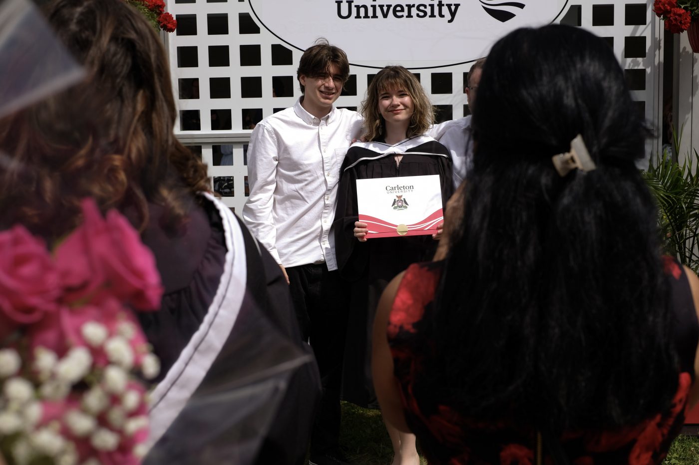 A recent graduate poses with supporters outside the Athletics Building.