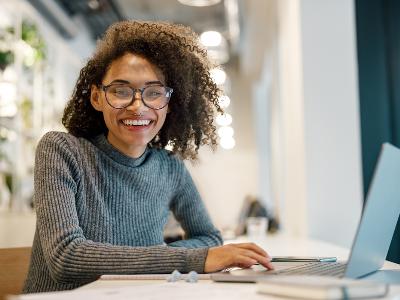 African American female university student looking at the camera while sitting at a desk with lap top open.