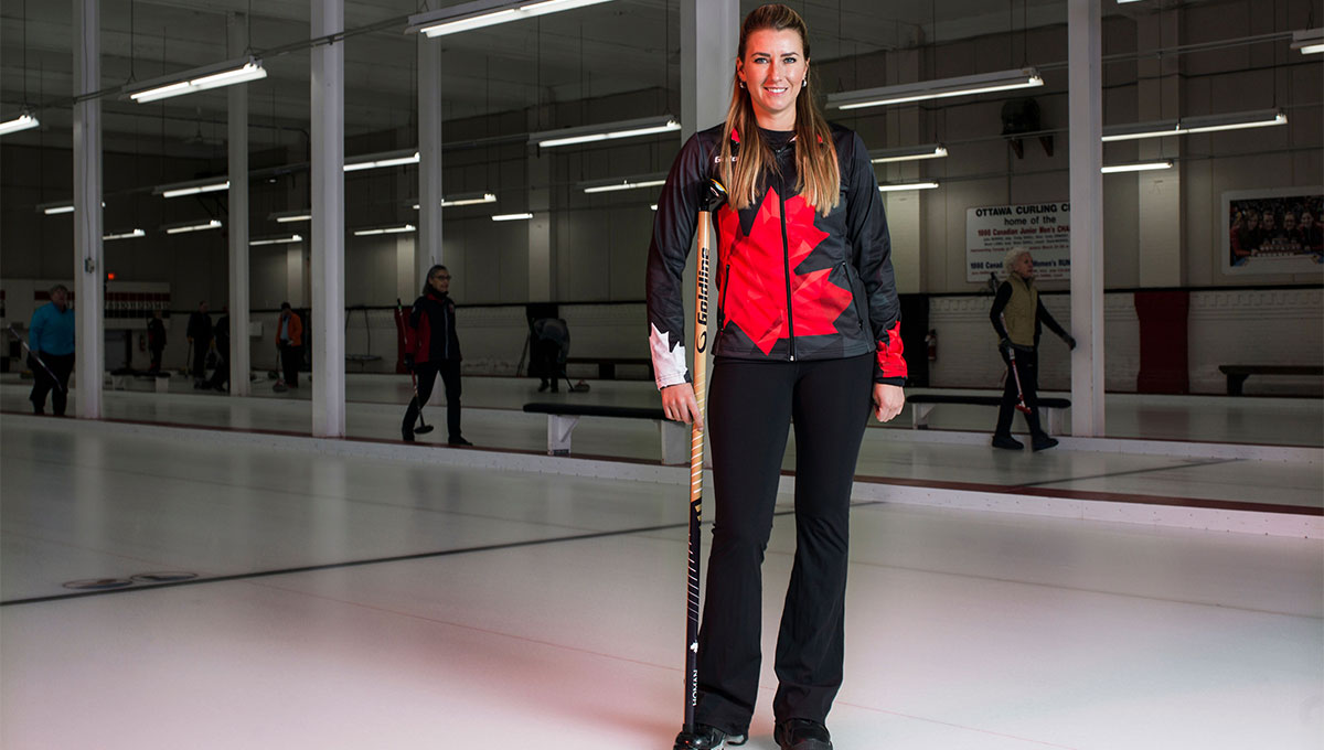 Carleton alum Emma Miskew stands in a curling rink.