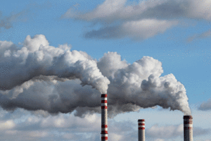 Factory smoke stacks release white clouds of pollution.