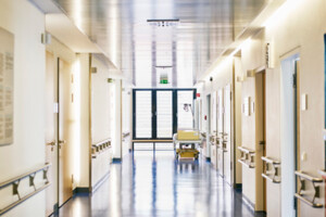 A hospital hallway with a medical bed near windows.