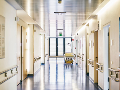 A hospital hallway with a medical bed near windows.