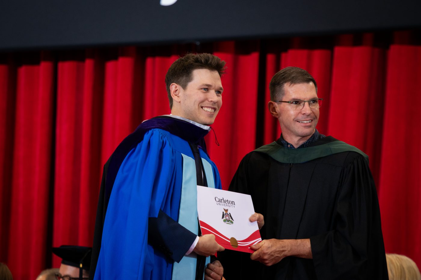 A graduating student receives his degree as he crosses the stage.