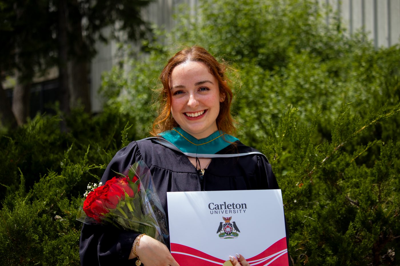 A student smiles as she poses with her degree.