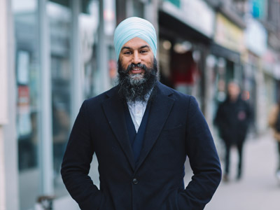 Jagmeet Singh stands outdoors and smiles at the camera