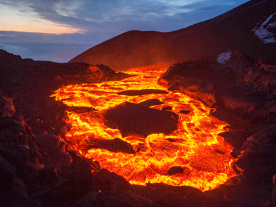 A lake of lava glows orange surrounded by mountains.