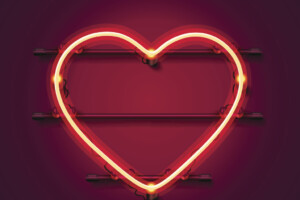 Neon heart signboard on the red background.