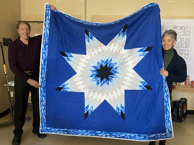 Adjunct Professor Lyette Fortin displays the blanket she received during her design studio class.