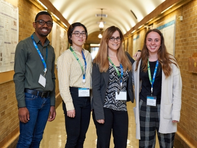 Panashe Kupakuwana, Vivian Chu, Stephanie DobbsNicole Adebar pose together in a hallway with a vaulted ceiling.