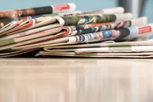 A stack of newspapers sits on a table.