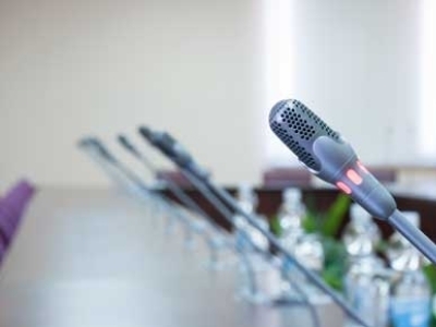 Microphones line a panel table.
