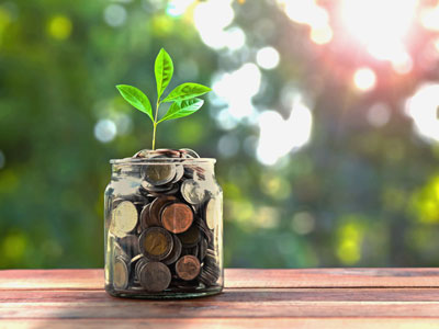 A jar of coins sprouts a plant, representing the concept of philanthropy