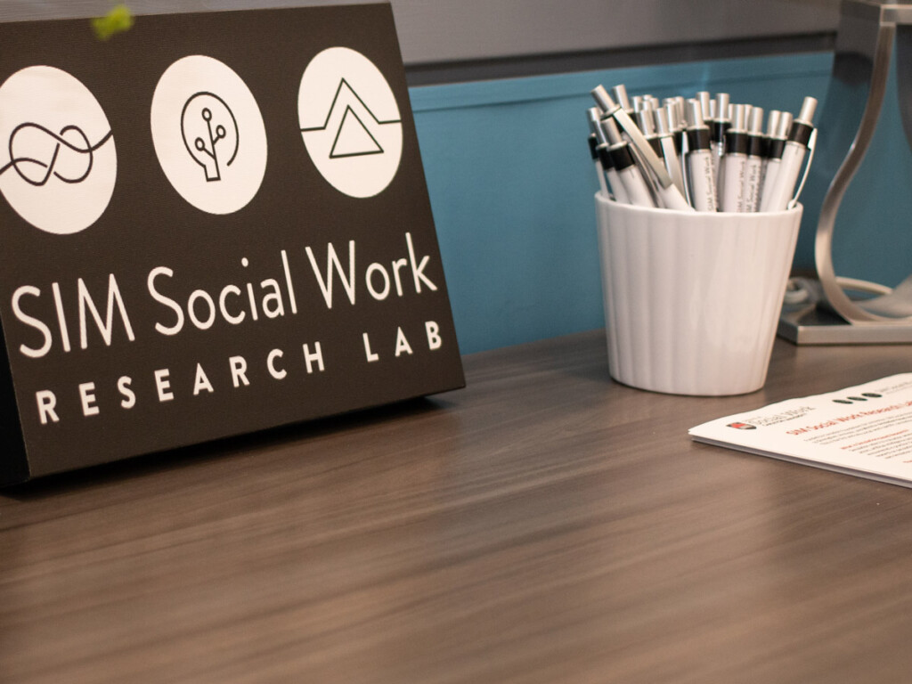 A SIM Lab sign sits on a desk next to a cup full of pens
