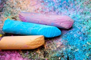 Three colours of chalk lay on the sidewalk.