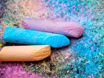 Three colours of chalk lay on the sidewalk.