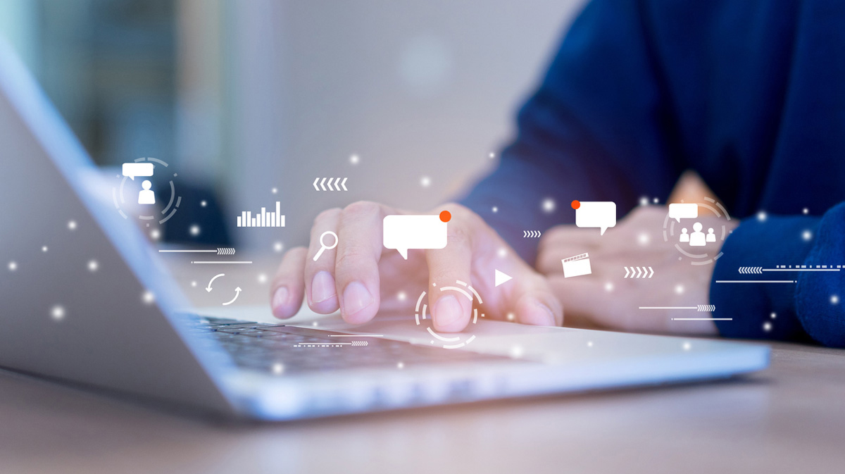 An artistic concept of online communication as represented by a close up of a person's hands typing on a keyboard.