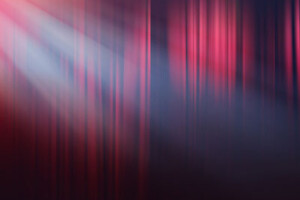 Light from a theatre spotlight shines on a stage curtain.
