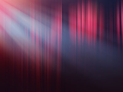 A spotlight shines on a theater curtain.