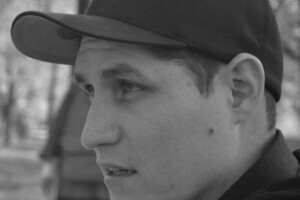 A profile shot of a young man wearing a baseball cap.