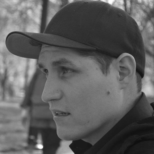 A profile shot of a young man wearing a baseball cap.