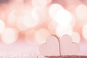 Two hearts lie on their sides next to each other on a wooden surface.