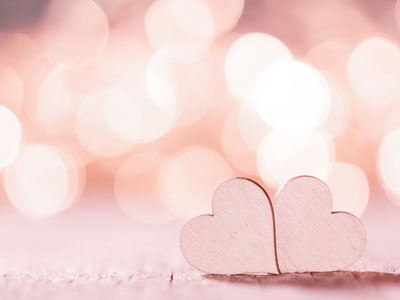 Two hearts lie on their sides next to each other on a wooden surface.