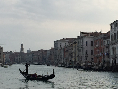A gondolier guides his boat through a canal in Venice.
