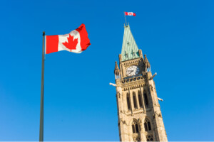 Close up of peace tower (parliament building) with a big canadian flag over blue sky in Ottawa, Canada