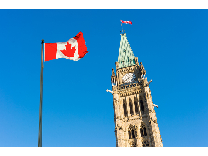 Close up of peace tower (parliament building) with a big canadian flag over blue sky in Ottawa, Canada