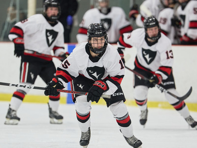 Three Ravens women's hockey team players skate on the ice.