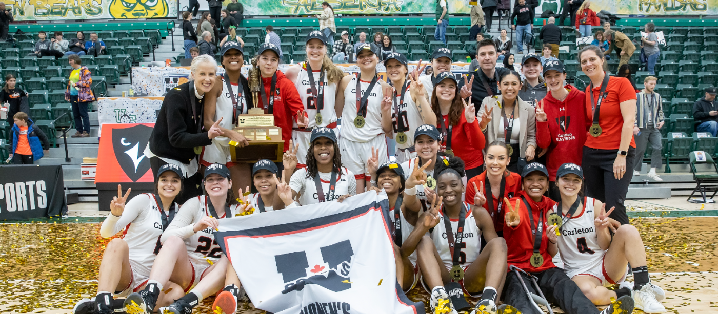 Women's basketball team posing on court with a trophy.
