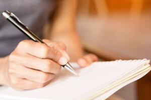 A woman writes in a notebook.