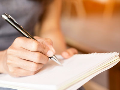 A woman writes in a notebook.