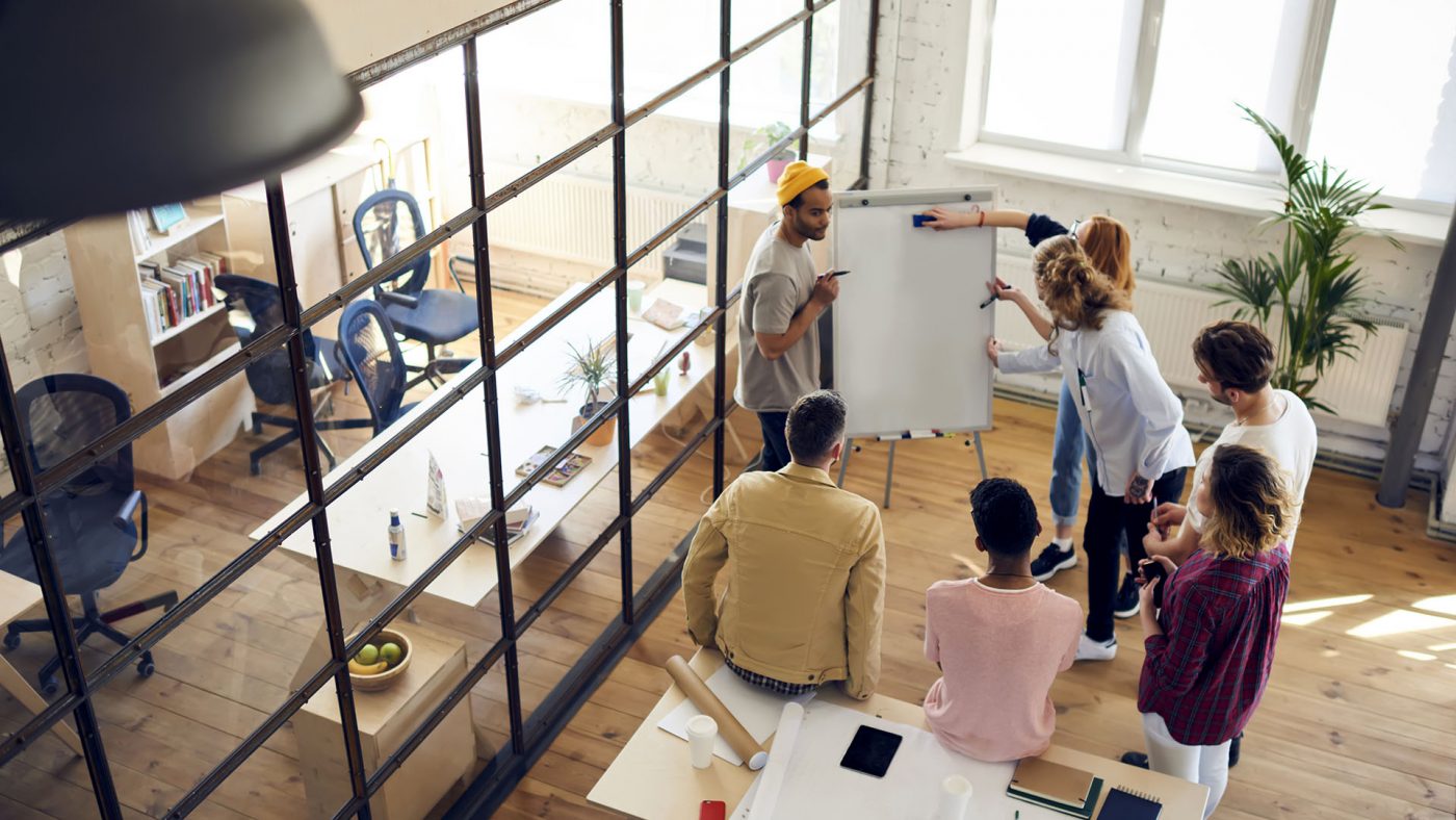 A group of people who appear to beworking together and using a whiteboard to write down ideas