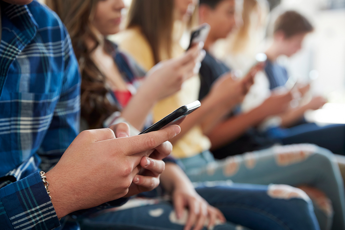 A row of users sitting down while using their mobile devices.