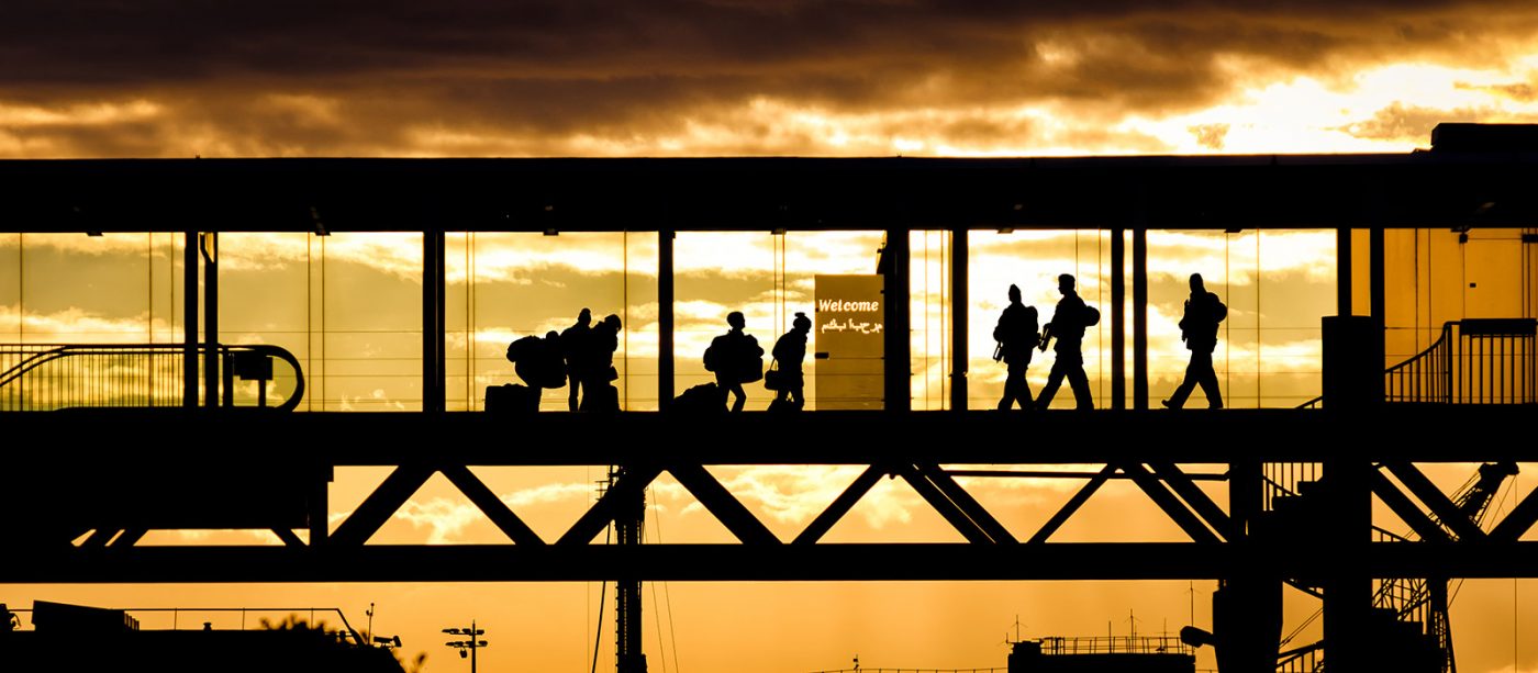 A silhouette of passengers walking through an airport terminal tunnel bridge